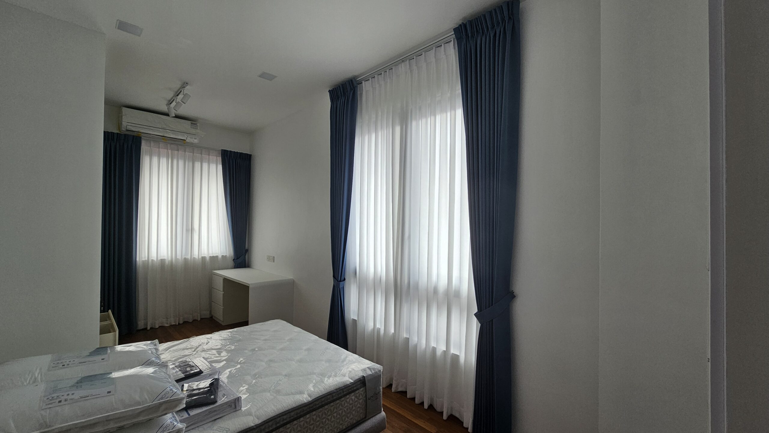 Shaped double pleat Dim-Out night curtains paired with sheer day curtains across two bedroom windows