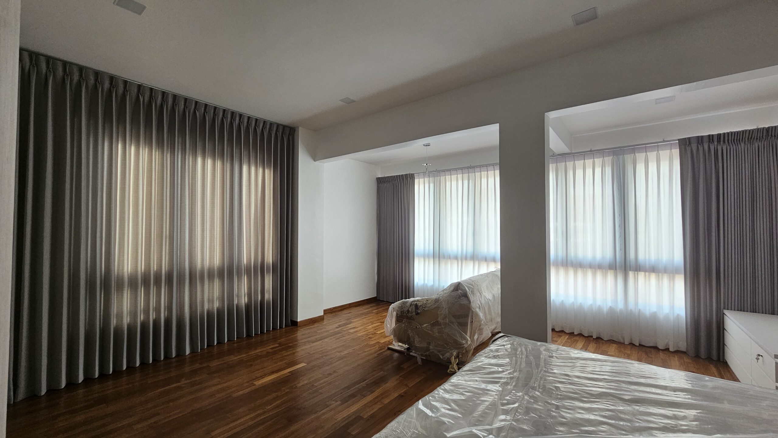 Shaped double pleat curtains closed on one window with sheer day curtains on adjoining windows