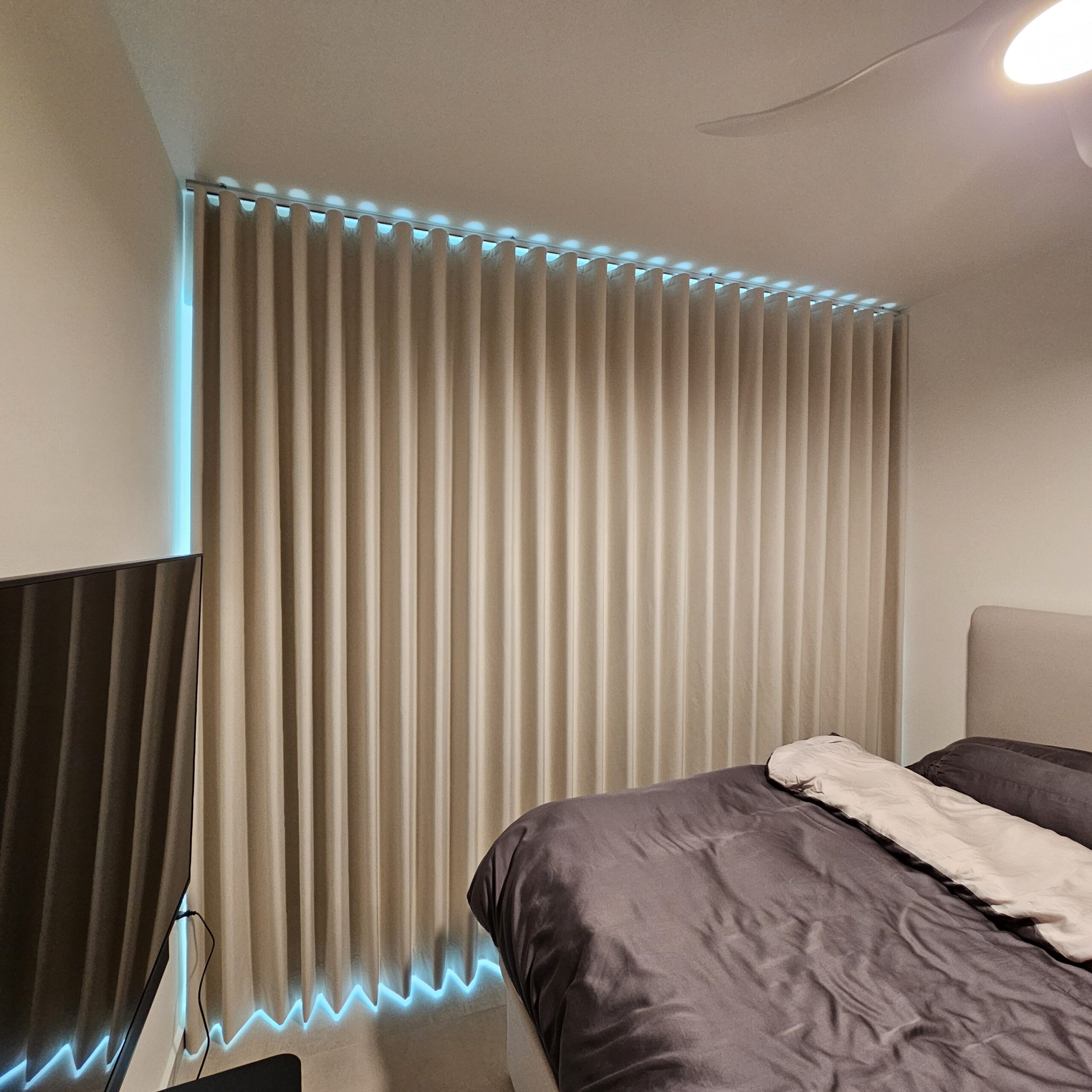 Full-height shaped ripple fold blackout curtains with smooth consistent waves in a bedroom