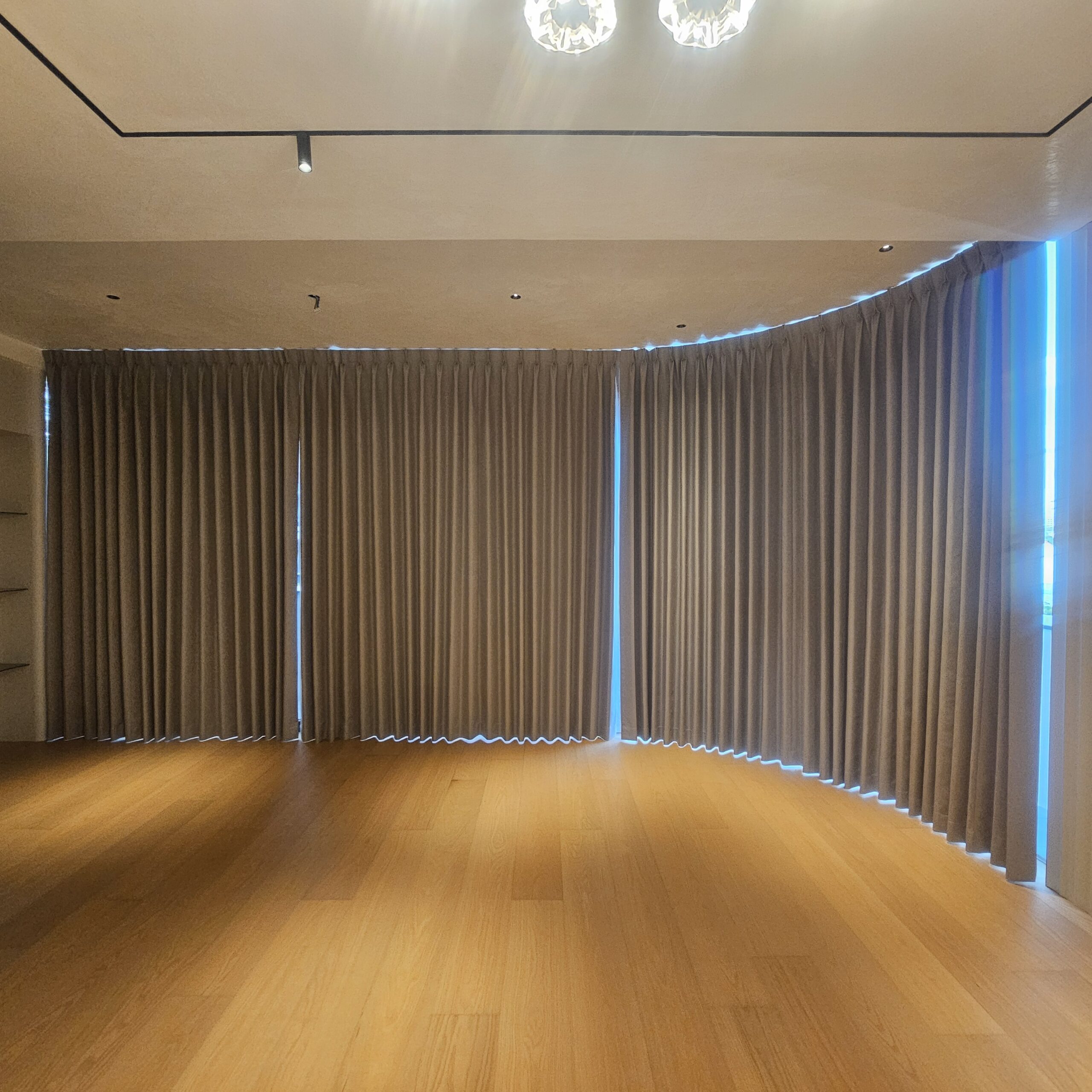 Full-height shaped blackout curtains following a curved window track in a residential space