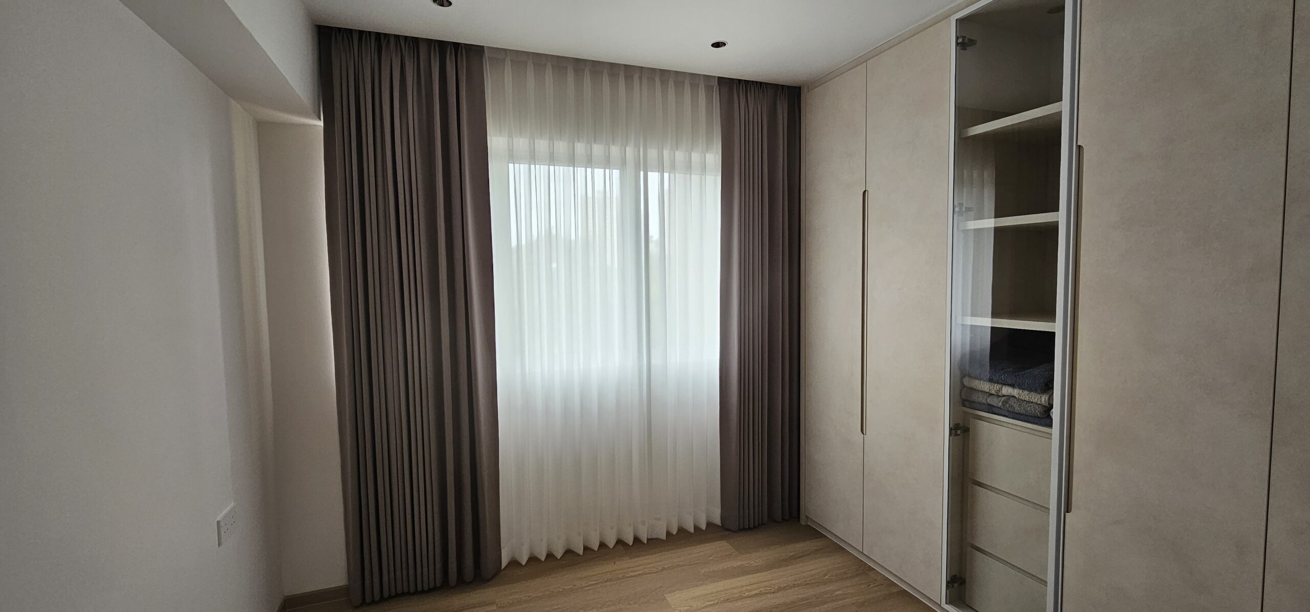 Shaped night curtains with sheer day curtains across a full-height bedroom window